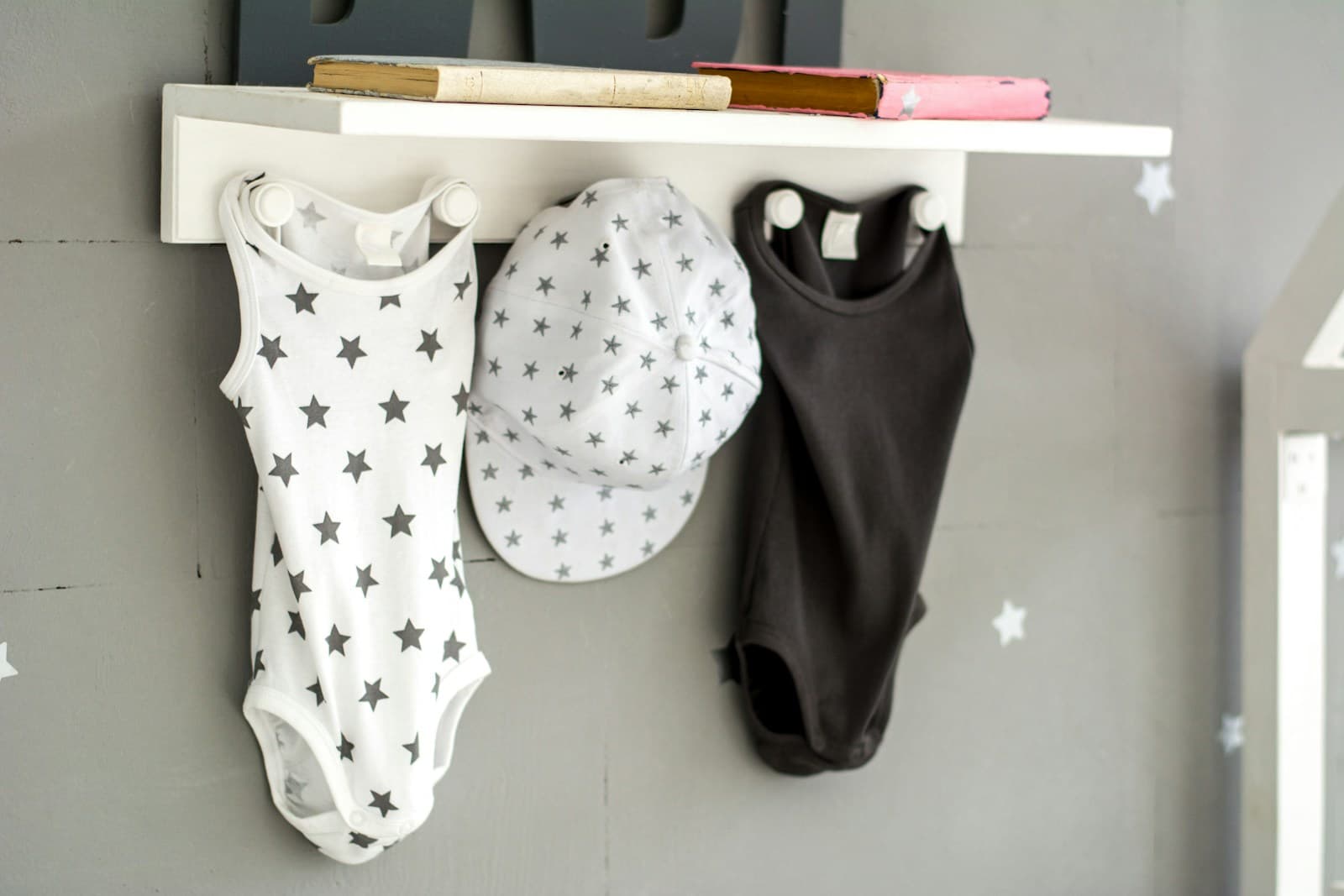 Un body et un bonnet de bébé suspendus à une patère.