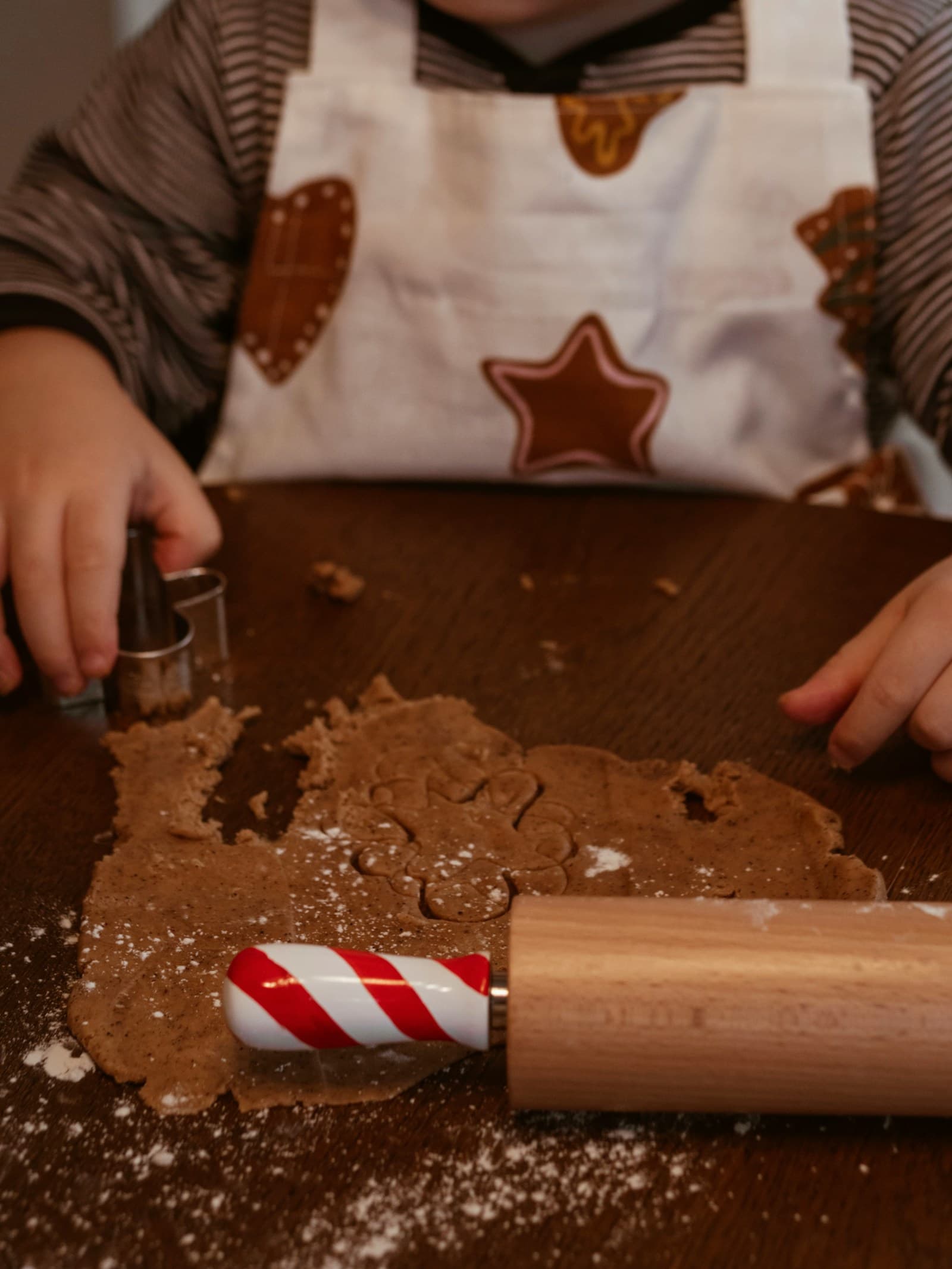 Un enfant découpe une pâte à biscuits avec des emporte-pièces.