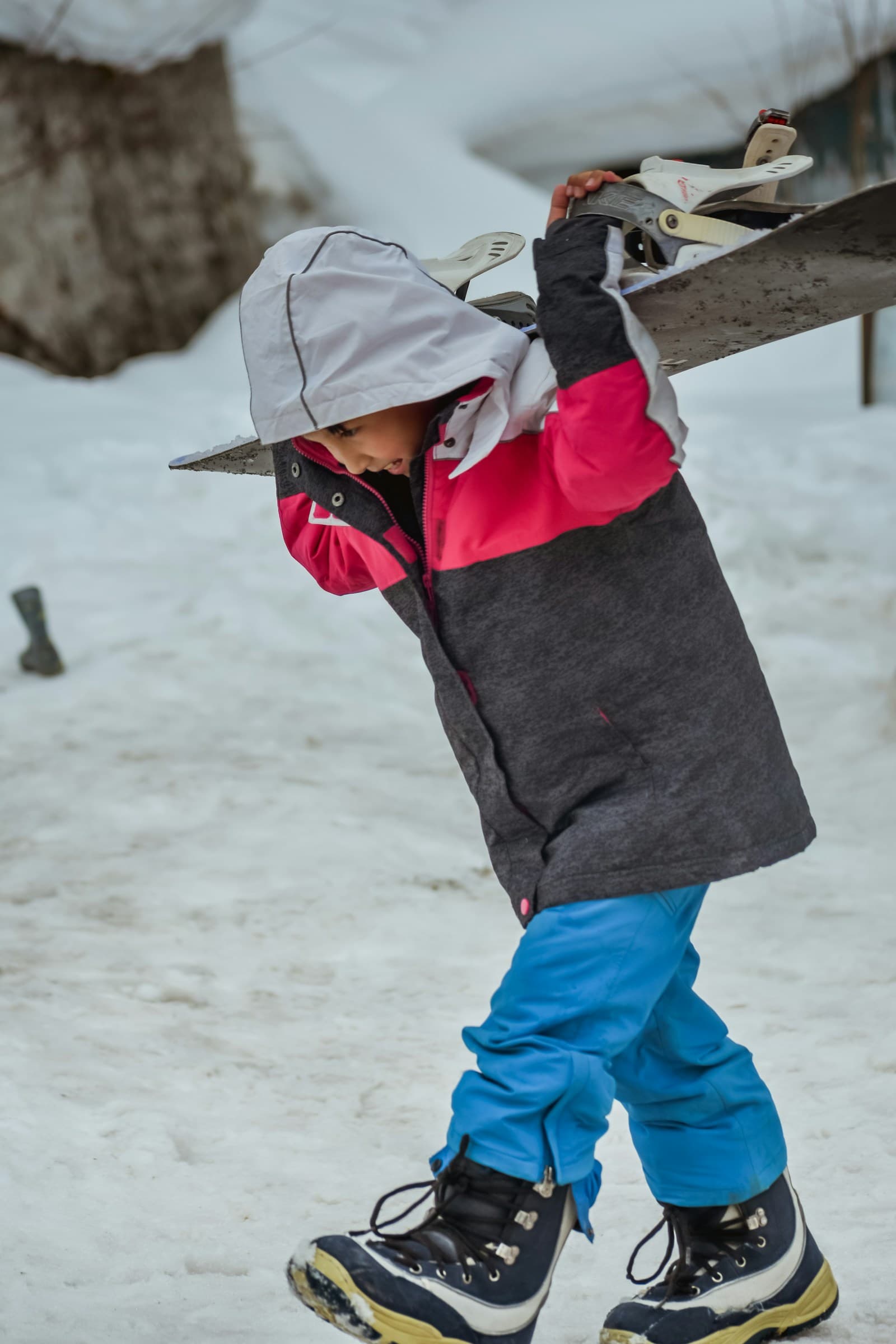 Un jeune enfant tient une planche sur un sol enneigé.