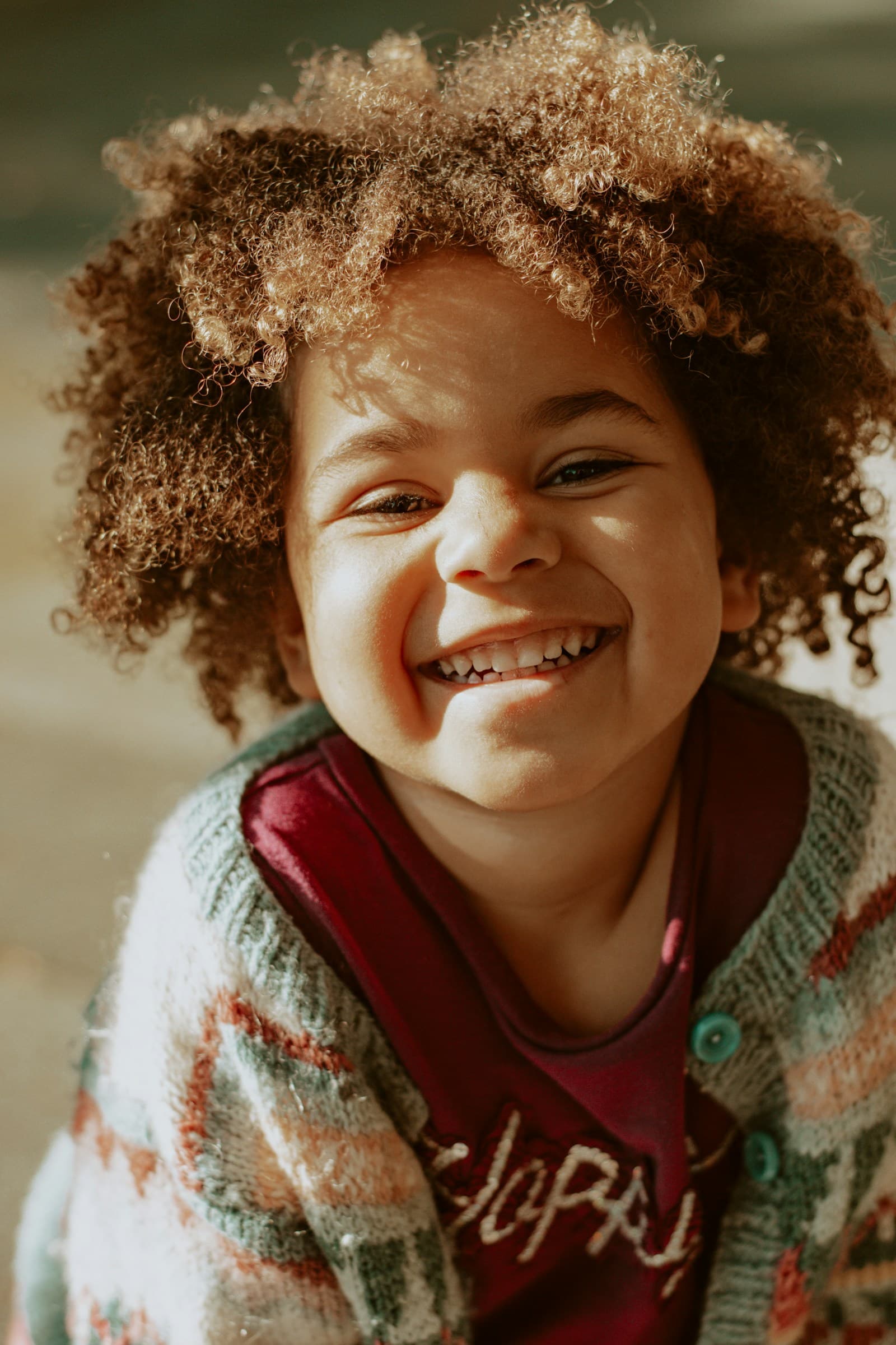 Une fille souriante porte un pull en tricot rouge et blanc.