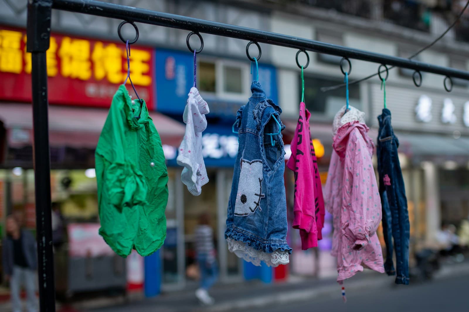 Des vêtements colorés suspendus à un portant, en extérieur.
