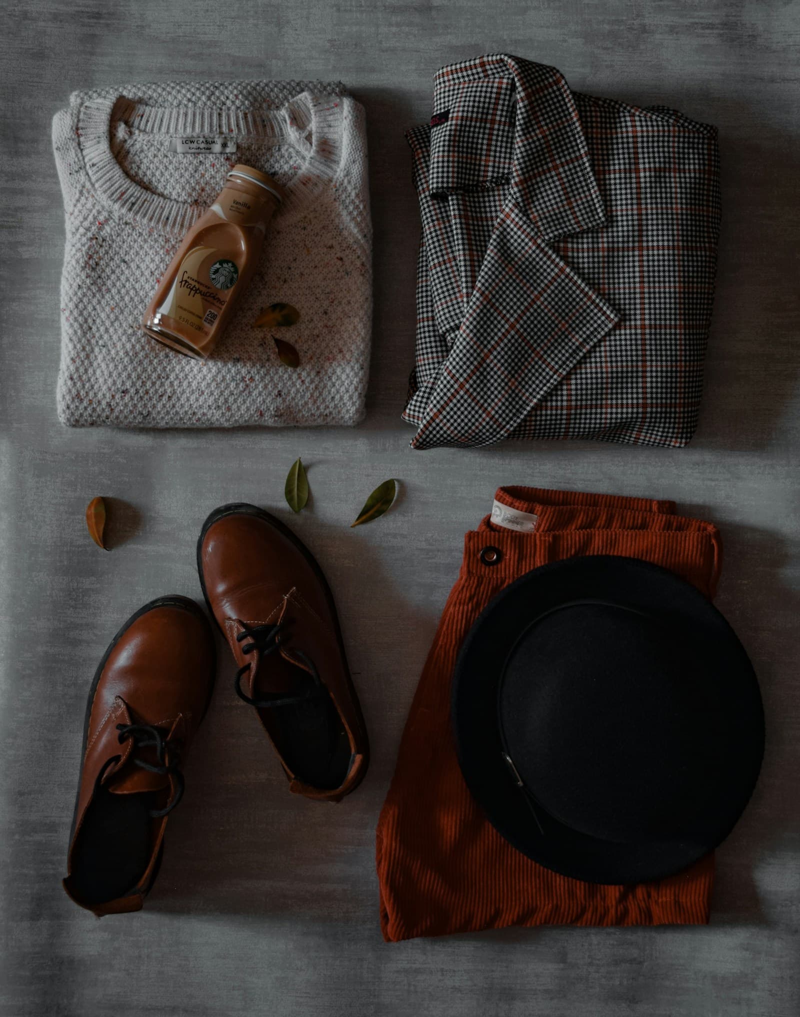 Une paire de chaussures, un bonnet et un pull posés sur un lit.